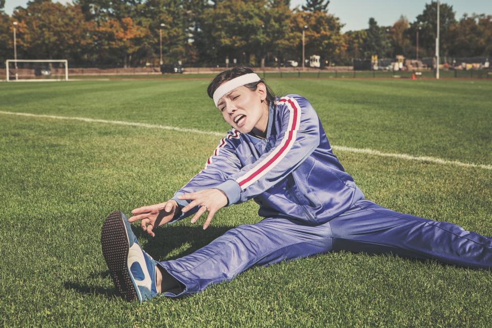 Iemand in een trainingspak stretcht op het gras