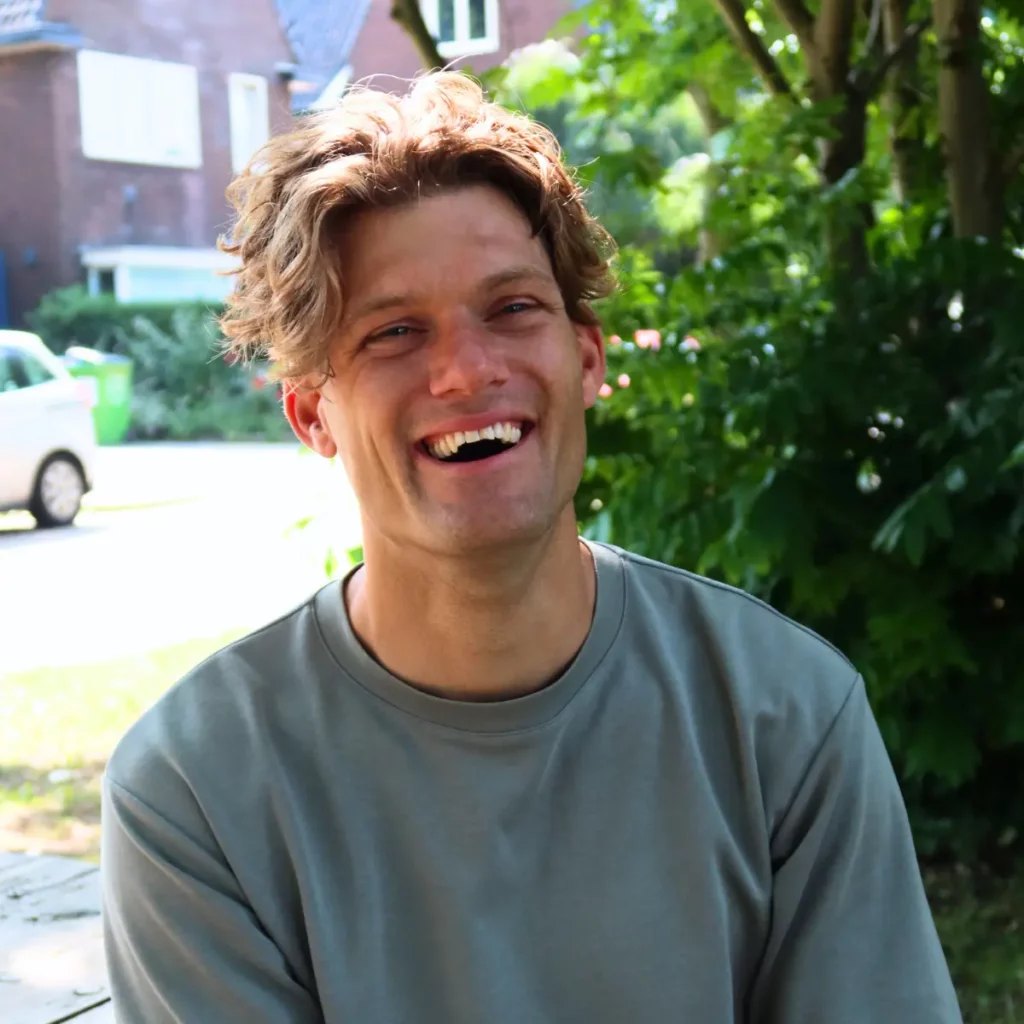 Jeroen lacht, buiten in een groene trui