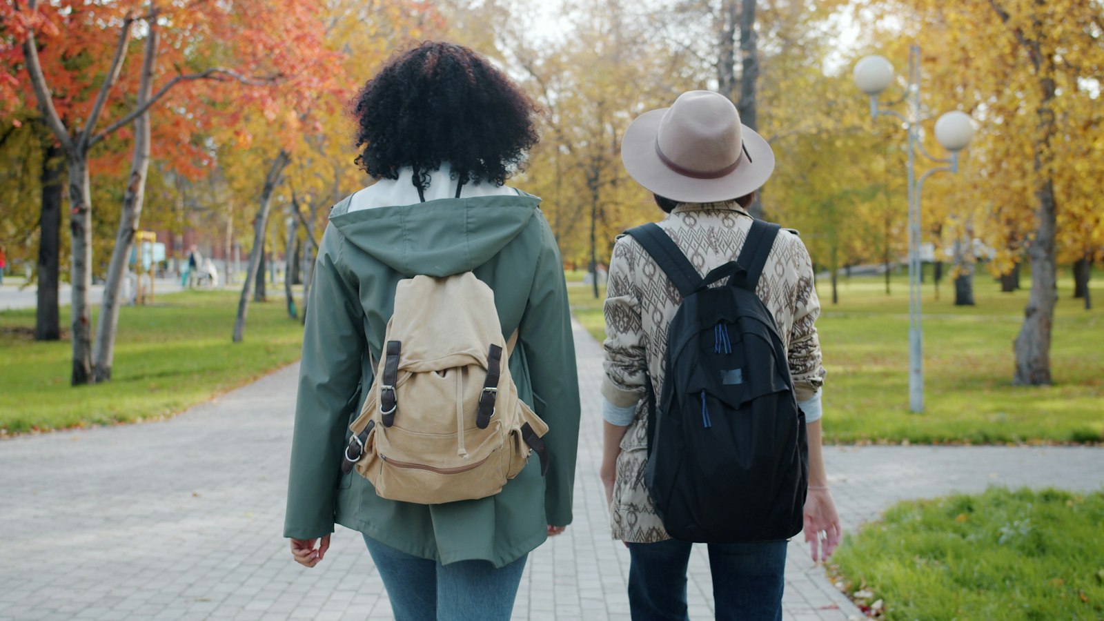 Twee mensen wandelen over een parkpad in de herfst